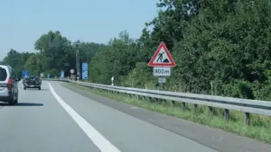 Ein Warnschild für Bauarbeiten an einer deutschen Autobahn mit Leitplanken.
