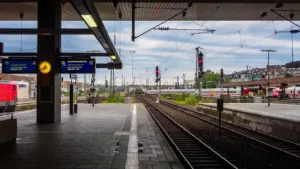 Blick auf einen leeren deutschen Bahnsteig mit Gleisen und digitalen Anzeigetafeln am Bahnhof.