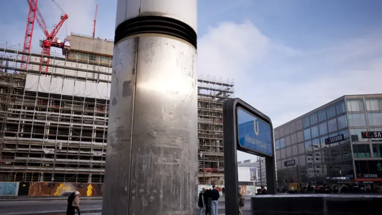 Baustelle am Berliner Alexanderplatz mit U-Bahn-Schild und Baukränen im Hintergrund.