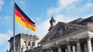 Deutscher Reichstag in Berlin mit wehender Flagge unter strahlend blauem Himmel.