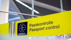 Ein gelbes Hinweisschild zur Passkontrolle an einem internationalen Flughafen oder Grenzübergang.