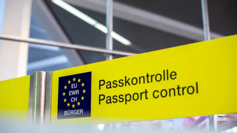 Gelbes Hinweisschild zur Passkontrolle an einem internationalen Flughafen in Europa.