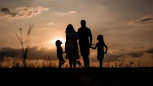 Familie beobachtet bei Sonnenuntergang gemeinsam den Abendhimmel während eines Spaziergangs im Freien.