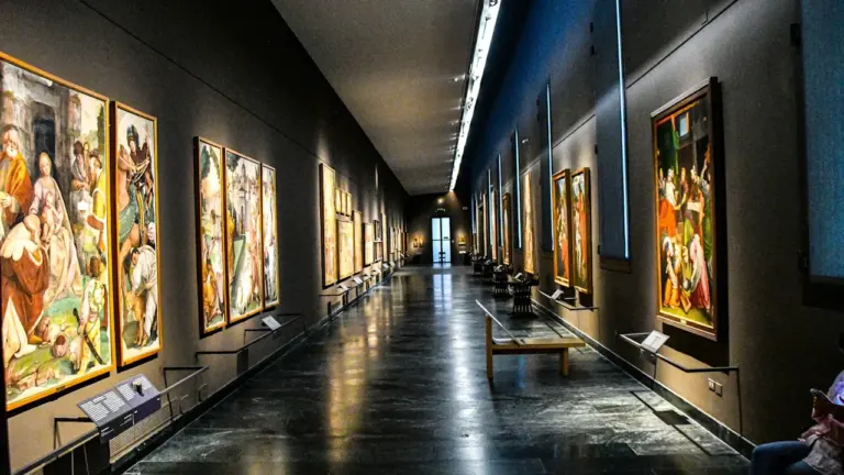 Langer, gut beleuchteter Flur in einem Museum mit zahlreichen Gemälden an den Wänden.