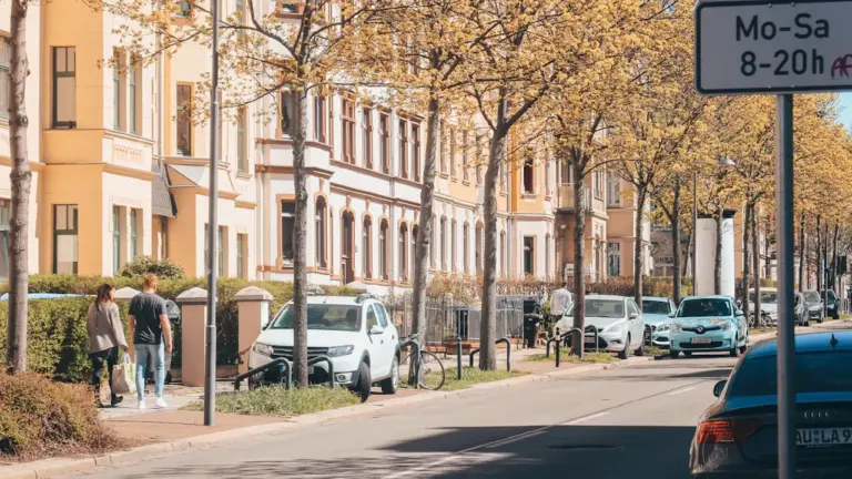 Eine typische Chemnitzer Straße mit Parkplätzen und Verkehrsschildern während eines sonnigen Tages.