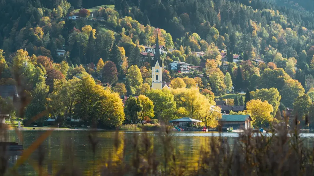 Malerische Kirche am Seeufer in einer bayerischen Berglandschaft bei Tageslicht.
