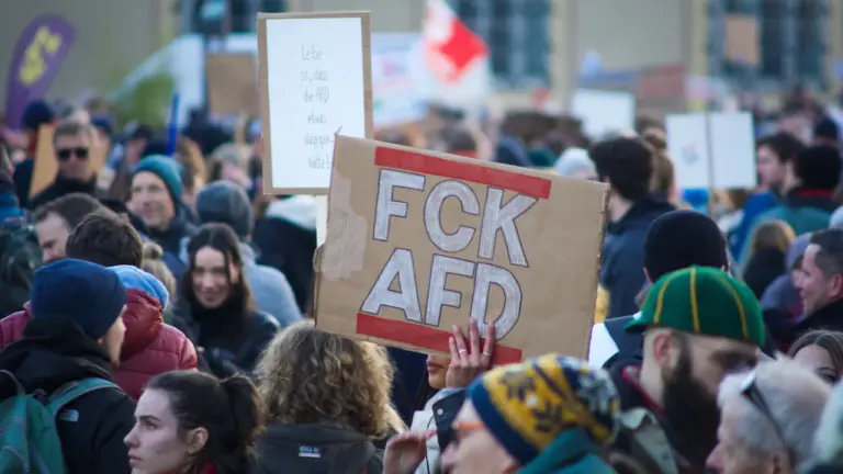 Menschenmenge bei einer Demonstration gegen die AfD mit einem handgeschriebenen Protestschild.