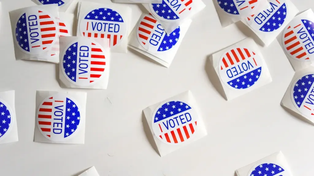 Mehrere 'I Voted'-Aufkleber mit US-Flaggen-Design auf einer weißen Oberfläche ausgebreitet.