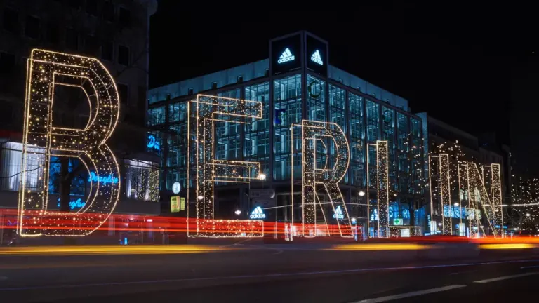 Leuchtender Berlin-Schriftzug bei Nacht vor einer modernen Stadtkulisse in Berlin.