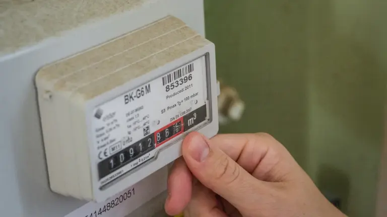 Nahaufnahme einer Hand an einem Stromzähler zur Überprüfung des aktuellen Verbrauchs.