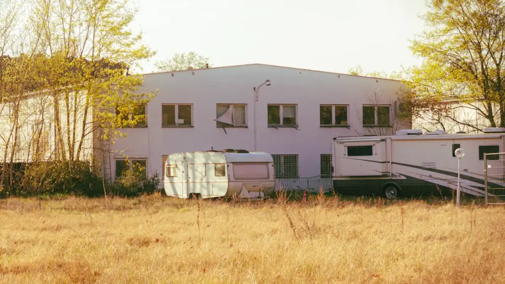 Wohnwagen stehen vor einem Bürogebäude auf einer Wiese in Potsdam.