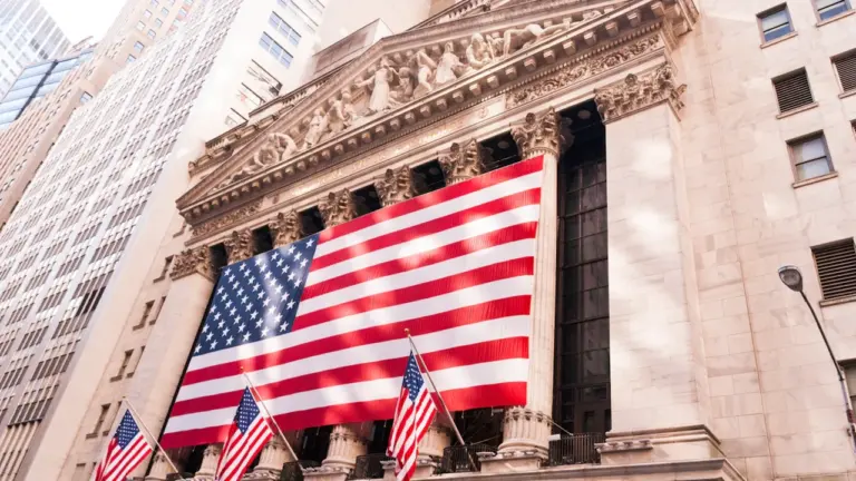 Die New York Stock Exchange mit amerikanischer Flagge an der Fassade in New York.