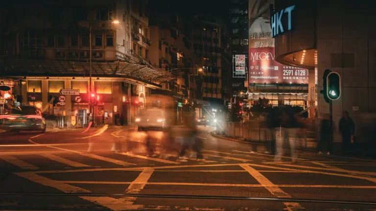 Belebte Stadtkreuzung bei Nacht mit verschwommenen Fußgängern im urbanen Zentrum.