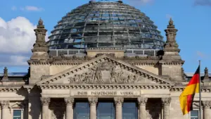 Das Reichstagsgebäude in Berlin mit Glaskuppel und deutscher Flagge bei sonnigem Wetter.