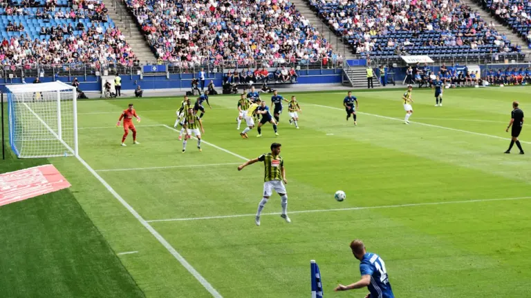Weitwinkelaufnahme einer professionellen Fußballpartie in einem großen deutschen Fußballstadion bei Tag.