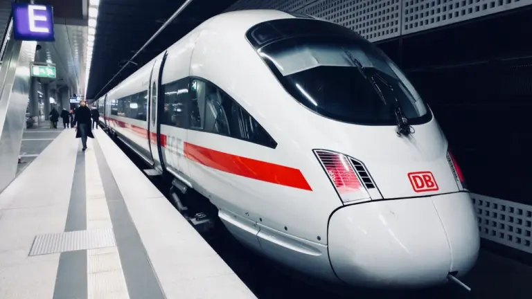 Ein weißer ICE-Zug der Deutschen Bahn steht an einem modernen Bahnhof bereit.
