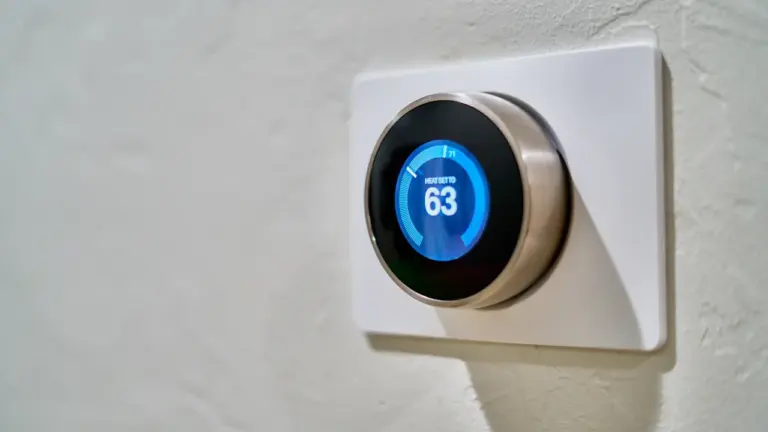 Modernes digitales Thermostat an einer weißen Wand zur Steuerung der Raumtemperatur.