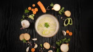 Cremige Kartoffel-Lauch-Suppe angerichtet mit frischem Gemüse auf einem dunklen Holztisch
