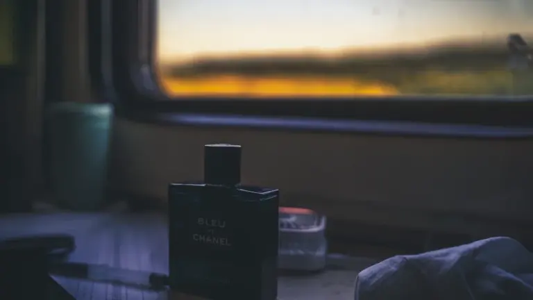 Eine elegante Parfümflasche steht bei Sonnenuntergang vor einem Fenster mit Ausblick.