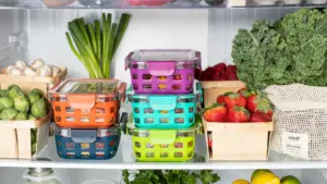 Blick in einen organisierten Kühlschrank mit frischem Gemüse und bunte Lebensmittelbehälter.