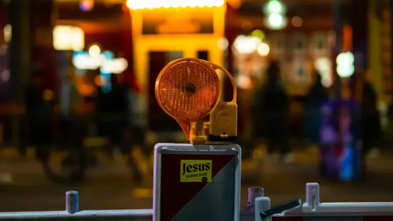 Orangefarbene Baustellenleuchte auf einer Absperrung bei Nacht, symbolisiert eine nächtliche Straßensperrung.