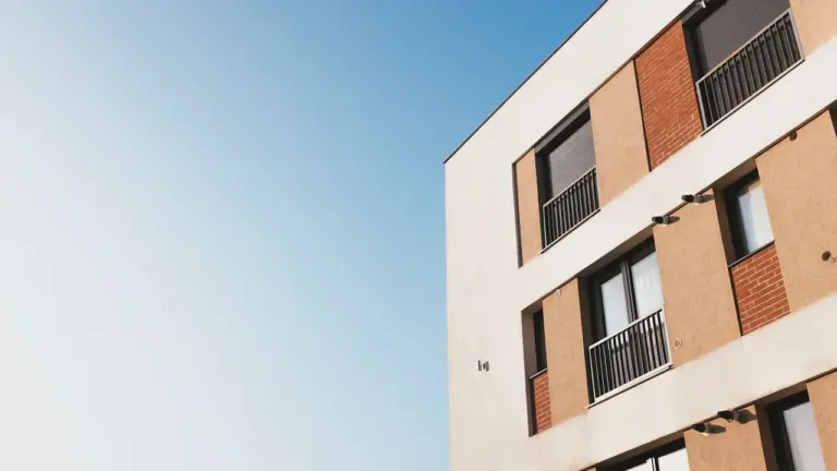 Moderne Fassade eines Wohnhauses mit Balkonen unter blauem Himmel in der Stadt.