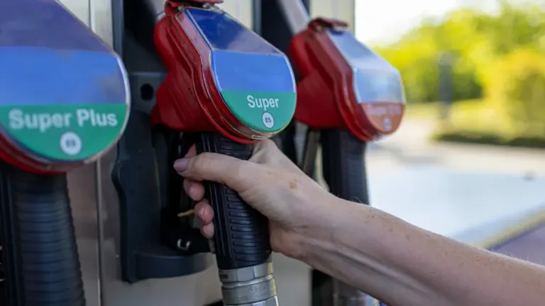 Eine Hand hält eine Zapfpistole an einer modernen Tankstelle beim Tankvorgang.