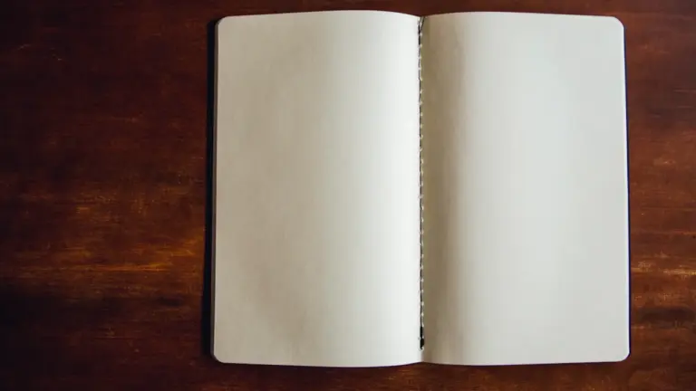 Ein leeres, aufgeschlagenes Notizbuch auf einem dunklen Holztisch für eigene Pläne.