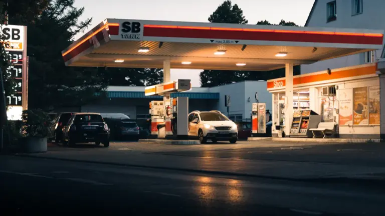 Eine beleuchtete Tankstelle in Deutschland mit Autos an den Zapfsäulen am Abend.