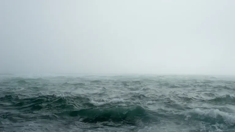Ein nebliger, düsterer Ozean mit bewegtem Wasser und minimalistischer, ruhiger Atmosphäre.