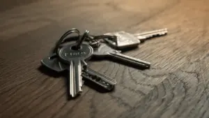 Ein Schlüsselbund liegt symbolisch auf einem rustikalen Holztisch im warmen Licht.