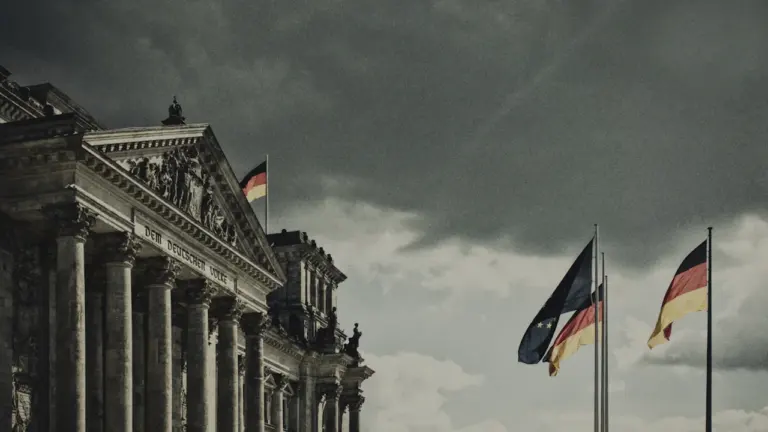 Die deutsche Flagge weht bei bedecktem Himmel über dem Reichstagsgebäude in Berlin.