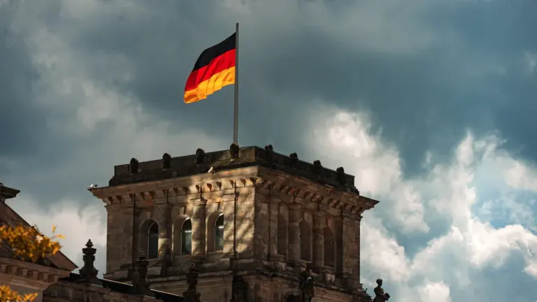 Deutsche Flagge weht auf dem Dach eines historischen Gebäudes unter bewölktem Himmel.