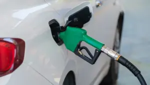 Zapfpistole beim Betanken eines weißen Autos an einer Tankstelle für den Kraftstoffvergleich.