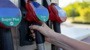 Eine Hand hält eine Zapfpistole an einer modernen Tankstelle für den Tankvorgang.