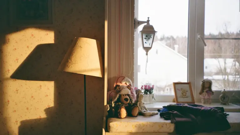 Warmes Sonnenlicht fällt durch ein Fenster auf nostalgisches Kinderspielzeug in einem ruhigen Raum.
